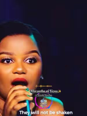 A medium shot features a woman with brown skin and dark hair, singing into a microphone. She has made up eyes and red lipstick and is wearing a top with visible straps. Overlayed text in a vibrant green font stating "Mwamba ni Yesu." The backdrop is dark, with accents of purple and blue, providing contrast to the woman. A logo with GM Gospel Minister is placed near her.
