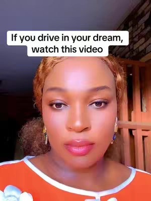 A close-up shot of a woman with light skin. She has brown eyes and red lipstick. Above her is a rectangular text box with the words "If you drive in your dream, watch this video". The background is soft and blurred.