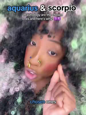 A close-up shot of a person with distinctive makeup, possibly of African descent, pointing a finger towards the viewer . The person has various piercings, including nose rings, and is wearing a top with a black collar. The overall composition is vibrant and eye-catching due to the strong color contrast.