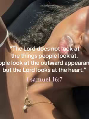 The image features a close-up of a person's face, angled slightly to the side. A gold necklace with a heart-shaped pendant hangs down, and text overlays the image. The background is softly lit with minimal distractions, keeping the focus on the face and text.