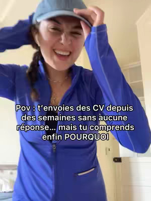 A woman wearing a blue track suit and a cap is smiling and gesturing towards her head. Text overlay is present at the bottom of the frame.