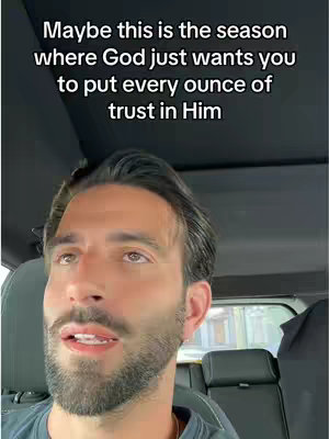 A man with a slight beard, in a car, looks up and slightly left towards the light in the image, with overlay text at the top. The background is dark, with a visible car seat and window.