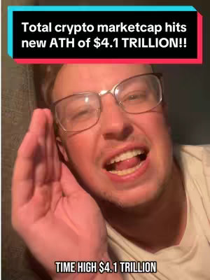 A man with glasses leans towards the camera with an excited expression, his hand raised near his mouth as if imparting a secret. Overlayed text announces a financial milestone.