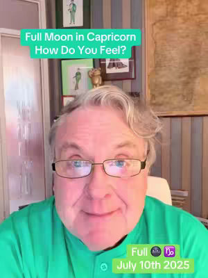 A middle-aged man with glasses and a green shirt is centered, with overlay text indicating the video covers the Full Moon in Capricorn on July 10th, 2025. The layout is typical of a selfie video, with the speaker in the foreground and a blurred background of a room with framed pictures and wall decor.
