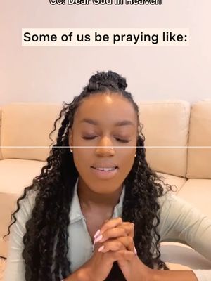 A woman with long, curly black hair and closed eyes is centered in the frame, with her hands clasped in front of her chest, as if in prayer. She is wearing a light green collared top. The background is a blurred-out cream-colored couch. Above her is text overlaid on the image, and more text can be seen at the top left corner. The overall lighting is soft and diffused.
