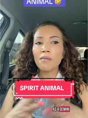 A woman with curly brown hair and large hoop earrings is seated inside a car, looking up slightly, with overlay text boxes. The top right has a rectangle that reads "ANIMAL" with a laughing emoji. The center has a large, red rectangle that reads "SPIRIT ANIMAL" in stylized white font. Below reads "AS A GEMINI".