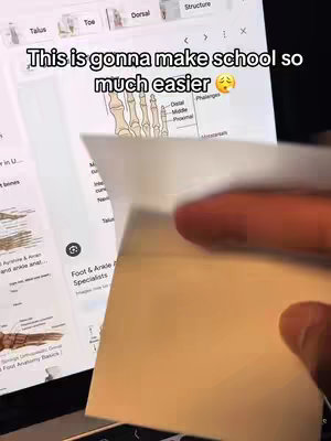 A person's hand holding a blank piece of paper in front of a laptop screen displaying a webpage with text and images of the foot and ankle anatomy. The upper portion of the screen shows the text overlay, with a sad face emoji.