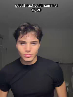A young man with dark hair and light skin is centered in the frame. He is wearing a black t-shirt. The background is a soft, blurred gray. A text overlay at the top reads 'get attractive till summer 17/20'.