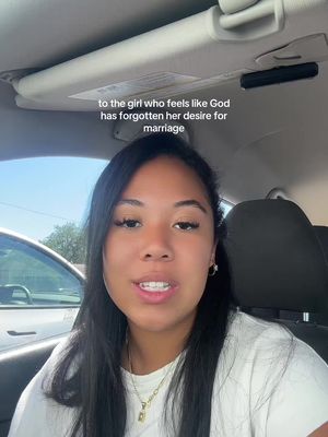 A woman with dark hair is in a car, looking towards the camera and speaking. Text overlayed on the image reads, 'to the girl who feels like God has forgotten her desire for marriage'. The lighting is soft, and the background shows the interior of a car.