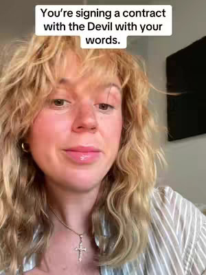 A selfie-style video featuring a woman with blonde, wavy hair. The background includes a plain white wall and a large black TV. She wears a striped button-down shirt and a silver cross necklace. Overlay text appears at the top, adding context to the video content.