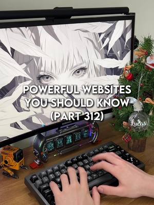 A person's hands are shown typing on a black keyboard. The keyboard is placed on a wooden desk, with other tech items behind it: The screen of a computer monitor shows images of eyes and hair of what appears to be a female character. Behind the screen is a Christmas tree. Various electronic devices are placed on the desk. The lighting is bright.
