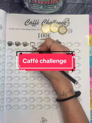 The image shows a hand filling in a box of a savings tracker booklet. The words "Caffè Challenge" are in a red box overlay. The booklet is open on a table, with a Nutella jar visible in the background. There's text on the page with coffee cup outlines, and some Euro coins are placed on the top.