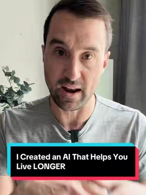 A man is centered in the frame, looking directly at the camera and slightly open-mouthed in a speaking gesture. He has short brown hair and is wearing a gray t-shirt. Behind him is a lightly colored wall, with a glimpse of plants to the left, and a tall white structure. A black horizontal bar at the bottom displays the text overlay.