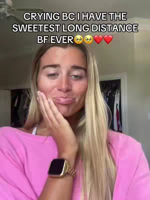 A woman with long blonde hair and a pink top covers her mouth with her left hand, looking at the camera with a pensive expression. Text overlays the image, and the background is a blurry interior space.