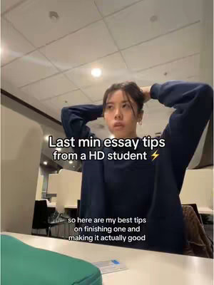 A young woman with dark hair, wearing a navy blue sweater, is in a well-lit room. She is looking up with her hands behind her head; The background includes a white ceiling with lights, a table, and chairs, suggesting a study or library environment. Text overlays indicate the video's content.