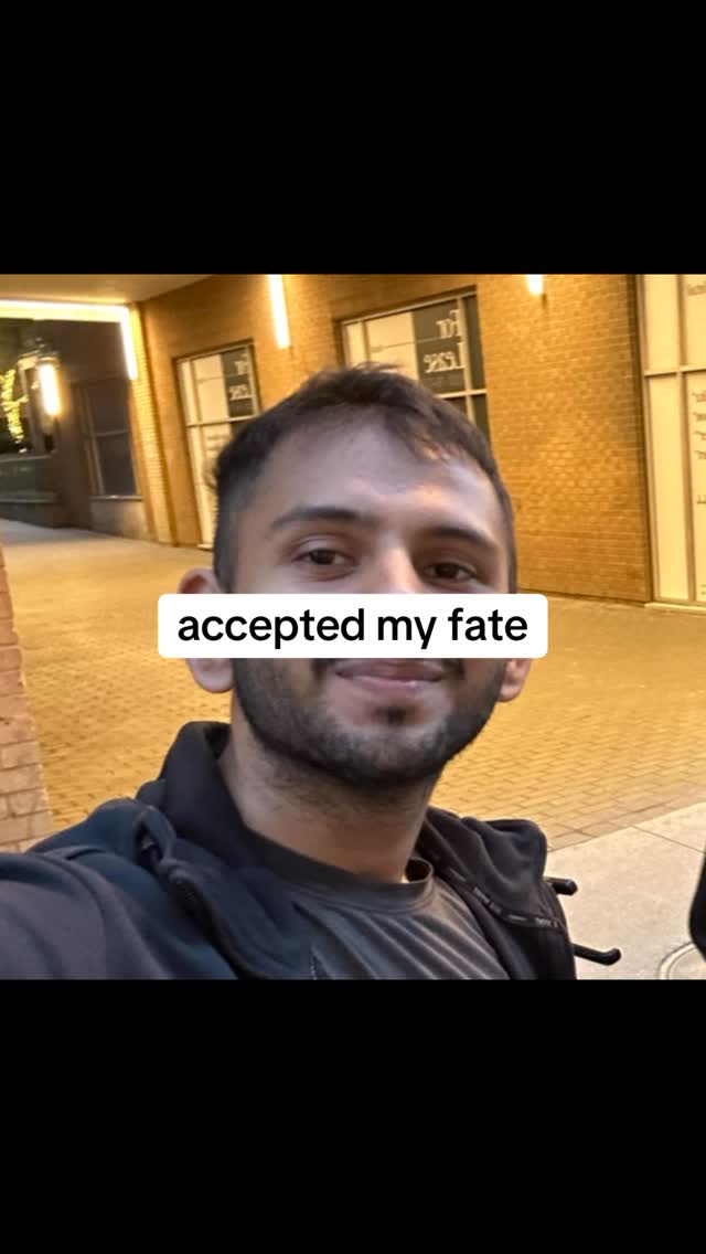 The cover image shows a man in a hoodie taking a selfie. A white rectangular text overlay that says 'accepted my fate' covers part of his face. The background includes a brick exterior and lights.