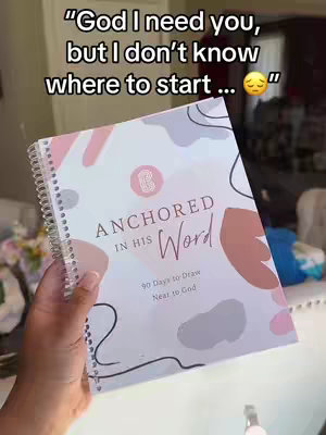 A person's hand holding a spiral-bound journal, with the title 'ANCHORED IN HIS Word'. The journal has a pastel color scheme with abstract shapes. Text overlayed on the top contains an emotional plea.