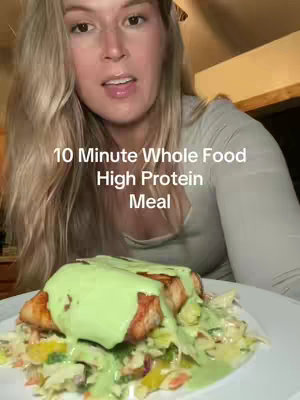 A woman with long blonde hair looks towards the viewer. Text overlay says '10 Minute Whole Food High Protein Meal'. In the foreground is a plate with food, including salmon and slaw with a green dressing.
