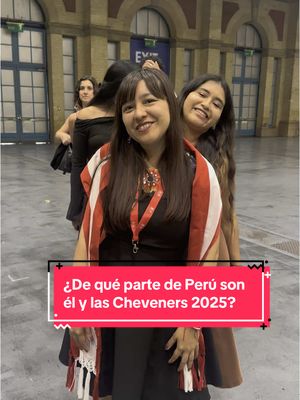 The image shows three women posing indoors. The central woman is smiling and wearing a Peruvian-style woven shawl in red, white, and brown. The other two women are smiling behind her. The background is blurred, but it appears to be an event space with light-colored walls and doorways.