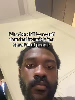 The image shows a close-up of a Black man's face. The text overlay is centrally placed on top of the frame. He has a short, dark beard and looks into the camera. The background appears to be a wall.