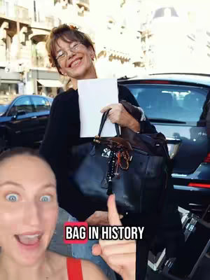 A woman with glasses smiles while holding a white paper and a black purse with a leather strap. Standing next to a car, the woman seems to be outside, possibly on a city street. A text box overlays with the words 'BAG IN HISTORY'.
