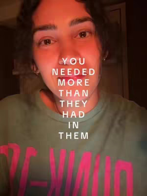 A close-up shot of a person's face, with text overlayed. The person has dark hair and is looking directly at the camera. The background is dark, and the overall lighting has a warm tone. The person is wearing a green shirt with a logo.