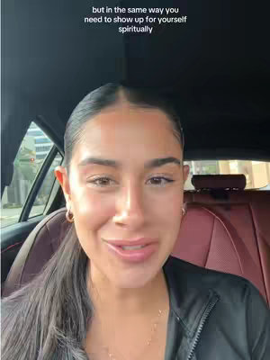 A woman with long black hair, pulled back, sits in a car, looking toward the camera and smiling. The car interior is visible with red leather seats. Text appears above her head.