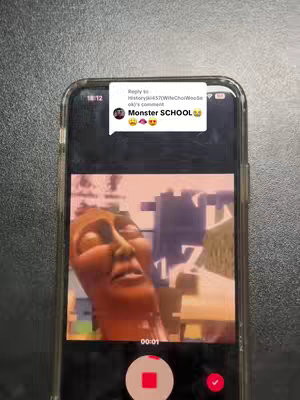 The cover image shows a smartphone displaying a frame from a video game. It presents a distorted, pixelated face of a giant creature, possibly a boss, with an open mouth. The phone screen is set against a neutral background. A comment overlay from another user saying 'MONSTER SCHOOL' appears in a speech bubble.