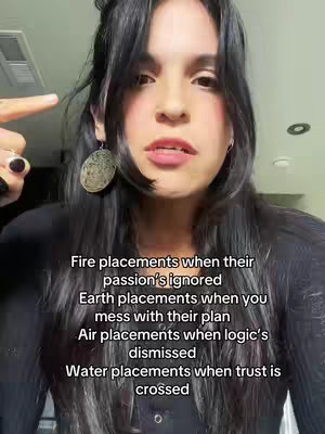 A woman with long, dark hair and large earrings is looking directly at the camera. She is pointing with one finger to her head. Text overlays detailing astrological placements is visible beneath her.