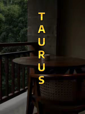 The image shows a balcony setting with a wooden table and chair. The background is blurred, showing green foliage, and the text 'TAURUS' in a golden, vertical font is overlaid on the image. The overall tone is calm and atmospheric.