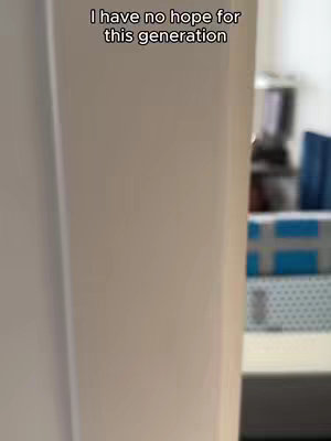 The image captures a close-up view of the edge of an off-white wall or surface, creating a vertical frame that dominates the shot. A slightly blurred background suggests an interior setting, with indistinct items such as books or a shelf barely visible. The upper portion of the image features overlaid text in a simple, modern font.