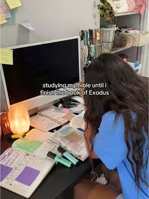 A person is studying at a desk, with a computer, papers, and books, showing signs of focused study.