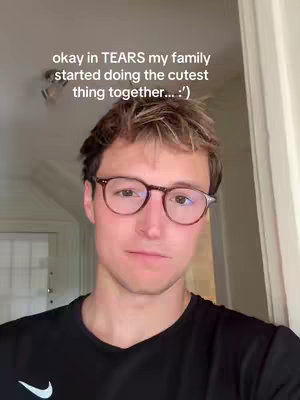 A man wearing glasses and a black shirt is centered in the frame, looking towards the camera. Text overlayed above him reads a message with an emotional tone, and in the background, a door and white wall are visible.