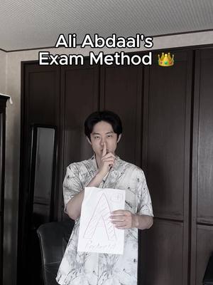 A young man stands in front of a dark brown door, holding a white paper with a hand-drawn 'A' on it. He gestures with his index finger to his lips, in a shushing motion. Text overlays the image. The background displays a minimalist, clean aesthetic, potentially within a home setup.