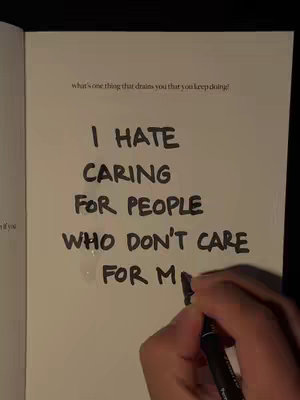 The image shows an open notebook with handwritten text in the middle. The text says, 'I HATE CARING FOR PEOPLE WHO DON'T CARE FOR ME.' A hand holding a black marker is visible near the bottom, as if writing more text.