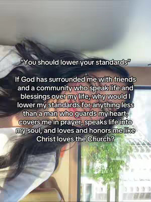 A selfie-style shot with a woman's face and hair filling much of the frame. Overlayed on the image is a quote in white text. The quote states, '"You should lower your standards". If God has surrounded me with friends and a community who speak life and blessings over my life, why would I lower my standards for anything less than a man who guards my heart, covers me in prayer, speaks life into my soul, and loves and honors me like Christ loves the Church?' The bottom of the image shows a partial view of a window with greenery visible through it.