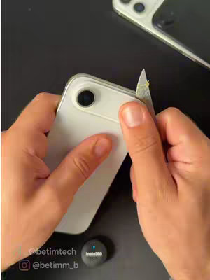 The image shows a pair of hands holding a white iPhone with a knife in the other, appearing to open the device. A second phone is in the background, and an Insta360 device is visible at the bottom.