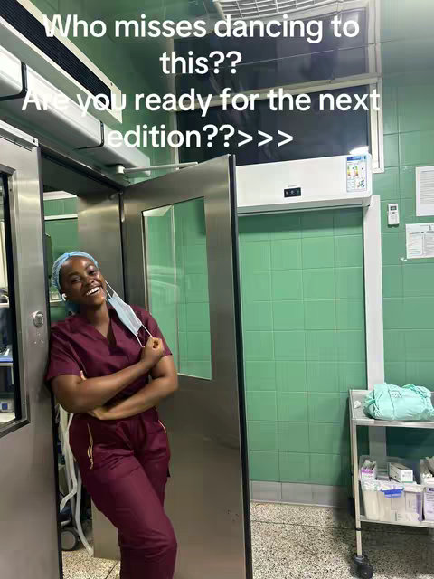 A young woman wearing a maroon scrub top and pants, a surgical cap, and a face mask is leaning against a metallic door frame. She is smiling, suggesting a positive, enthusiastic mood. The background is a sterile medical environment with green tile and a shelf. Text overlays are present on the top of the image highlighting this theme.