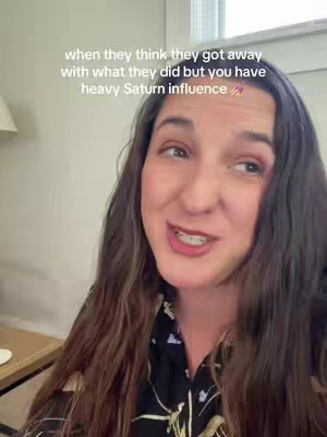 A woman with long brown hair is in an indoor setting, speaking directly to the camera. Text overlaid on the image reads, 'when they think they got away with what they did but you have heavy Saturn influence'. She is wearing a dark top.