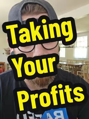 A man is centered in the frame, with a blurred background suggesting an indoor setting. The man wears glasses and a dark t-shirt. A text overlay that reads 'Taking Your Profits' in bold, yellow letters with a black outline covers the man's face.