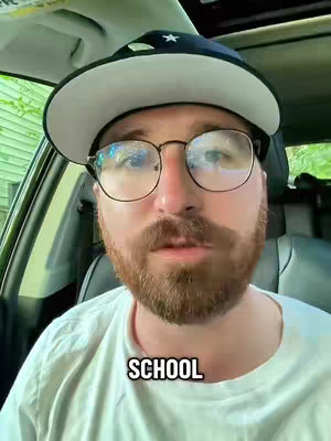 A man wearing glasses, a hat, and a white t-shirt is sitting in a car. The text overlay says 'SCHOOL'.