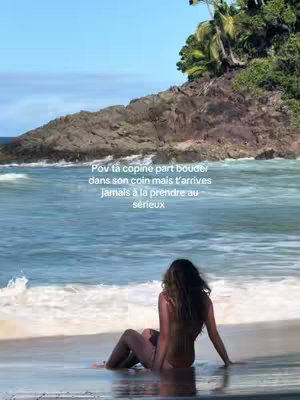 A scenic beach shot features a woman sitting on the shore. She is viewed from behind, her back facing the viewer as she looks out at the ocean. The image is framed by the natural elements of the beach and the water. A text overlay in the image adds a layer of storytelling.