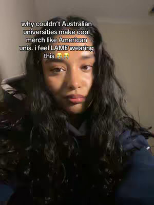 A young woman is centered in a medium shot, her dark hair flowing around her face. She wears a dark hoodie, with text overlaid at the image's top. Her expression appears contemplative or slightly sad, with a soft lighting.