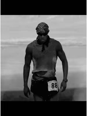The cover image is a monochrome photograph of a man running. The man is muscular and wearing a headband, sunglasses, a sleeveless shirt, shorts, and a bib with the number 88 on it. He appears to be in motion, set against a blurry background of a seascape under a cloudy sky.