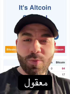 A man in a black cap is centered in a selfie-style shot. Behind him is a blurred screen showing text related to cryptocurrency. The man has a beard and a serious expression. A black rectangle at the bottom contains white Arabic text.
