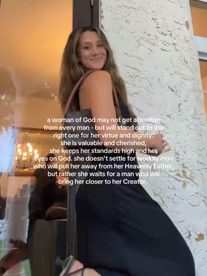 A young woman with long brown hair is standing indoors, slightly turned towards the camera with a soft smile. She's wearing a black dress and carrying a purse. Text appears on the image with a golden frame. The background is a mix of light and shadows, suggesting a well-lit interior space.