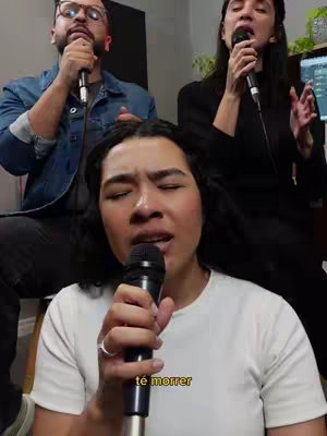 The cover image shows three people singing into microphones. In the foreground, a woman with dark hair is singing with her eyes closed, her face expressive. Behind her, and to the left, a man with glasses is also singing. To the right, another woman sings. The lighting appears natural, and the setting looks like a studio or a room set up for recording.