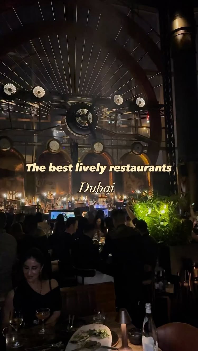 The cover image shows a dimly lit restaurant scene at night, filled with many people. In the foreground, there are tables and chairs, and a woman is at the table on the left, and in the background there is a bar where the bartenders are. The image has a dark, moody atmosphere with a few bright lights.