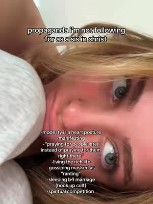 A selfie-style shot featuring a woman lying down appearing to be in bed. She is looking up towards the camera with her eyes and mouth partially open. The background appears to be a white bed sheet or comforter. Text overlays are present in the upper left of the image, written in black font.
