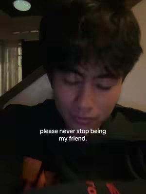 A close-up shot of a young man's face. He is looking down, and the background is blurred. Text on the image reads: 'please never stop being my friend.'
